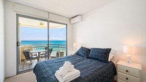 Et hotelværelse med en seng, et natbord, en lampe, en stol og havudsigt.