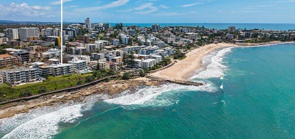 A coastal cityscape with a prominent hotel sign, beachfront, and dense residential buildings.