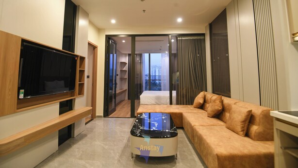 A modern living room with a flat-screen TV, a glass coffee table, and a brown sofa. - ICON40 Hạ Long • 2 Bedrooms • Ocean View • Full Kitchen (Thành phố Hạ Long)