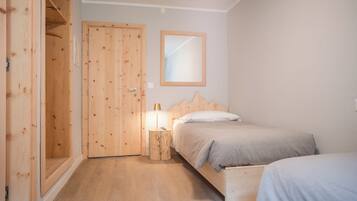 A bedroom with a wooden wardrobe, a bed with a wooden headboard, and a bedside table with a lamp.