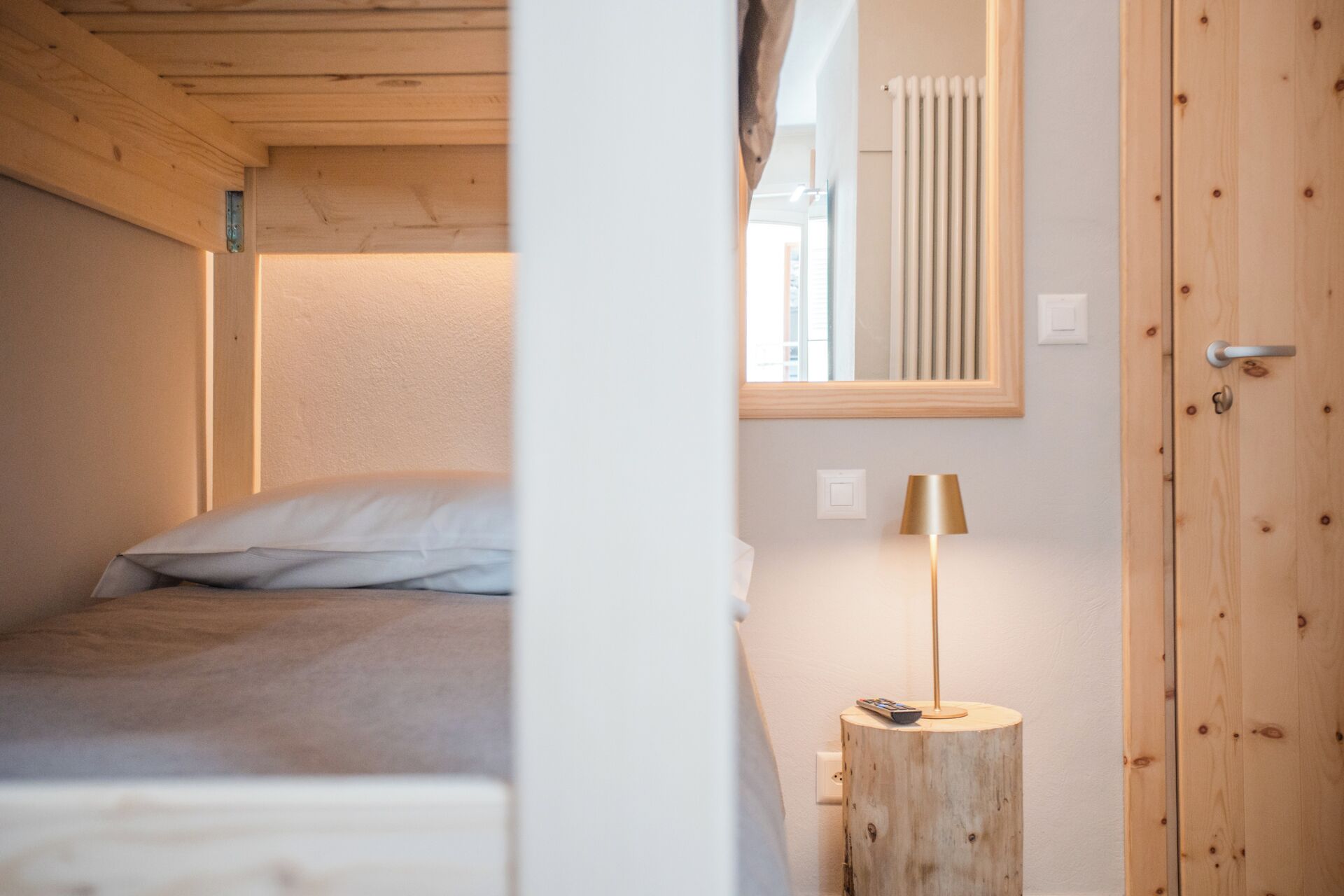 Un dormitorio con cama, mesita de noche, lámpara y armario de madera.