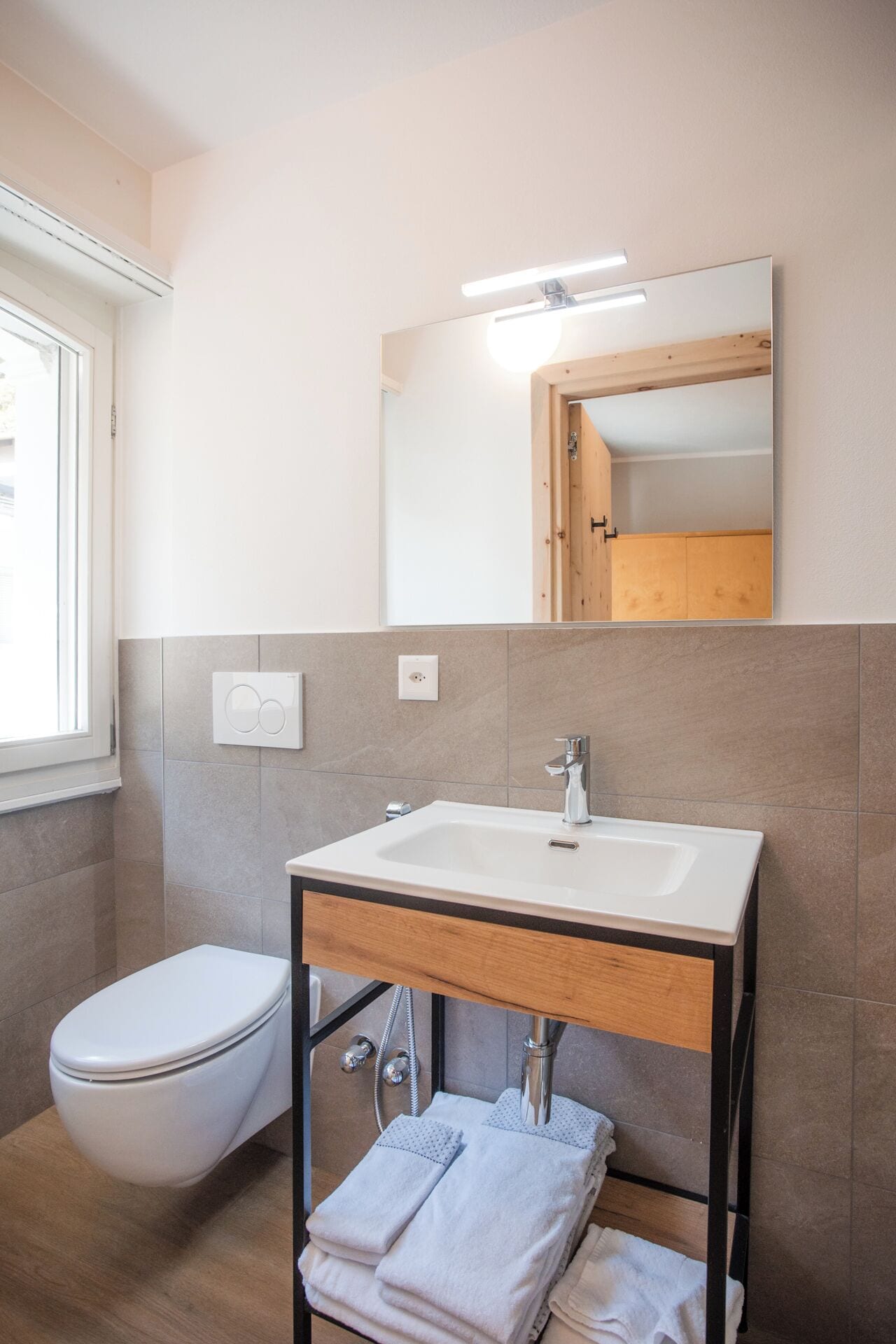 A modern bathroom with a toilet, sink, and mirror.