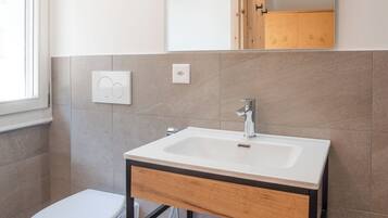 Un baño moderno con inodoro, lavamanos y espejo.