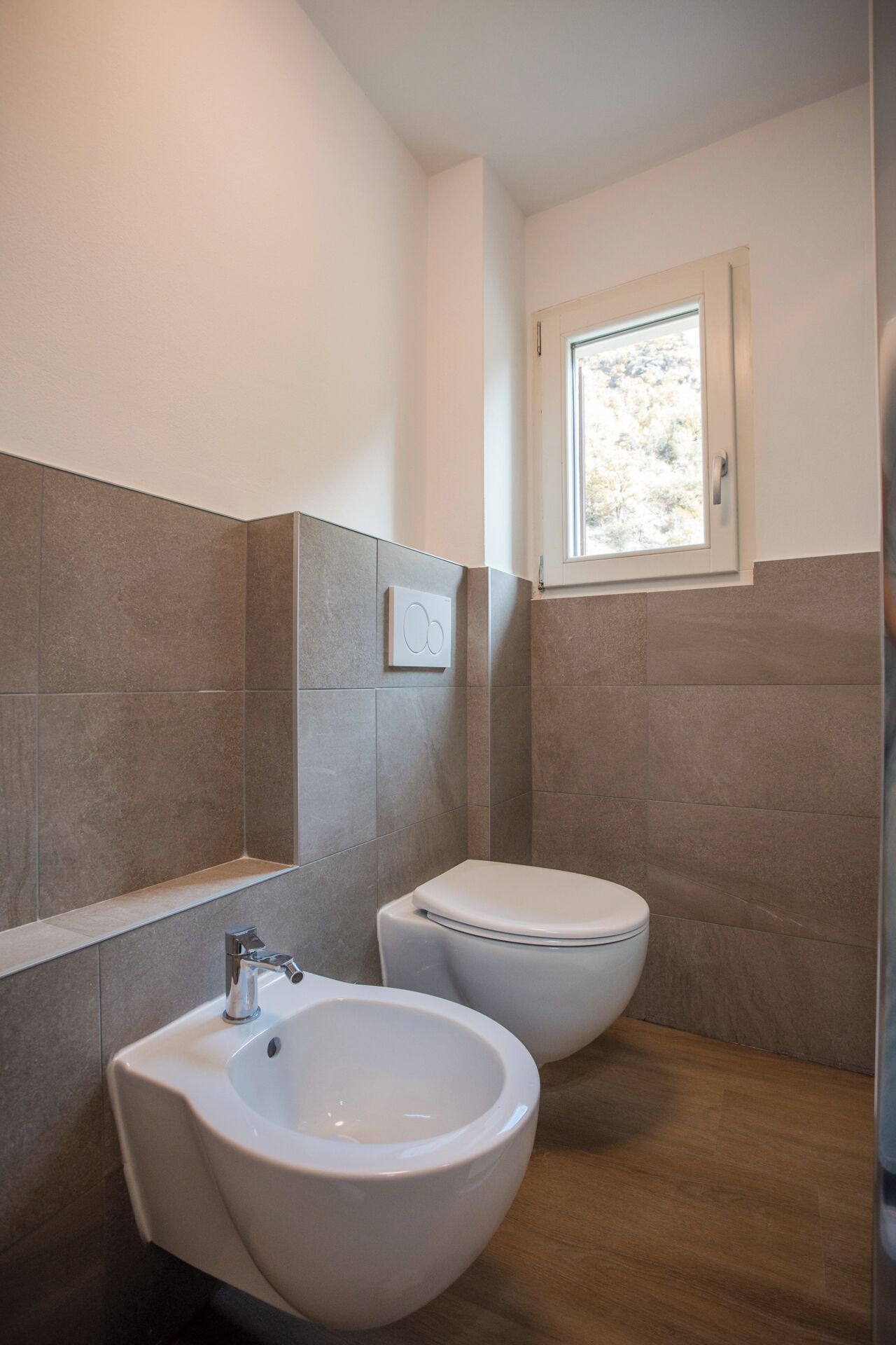 Une salle de bain équipée d’un bidet, d’un lavabo et d’une fenêtre.