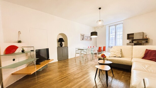 A spacious living area with a wooden floor, a white sofa, a glass coffee table, and a dining area with a glass table and chairs. - Gîte des Débats, ideal for families and friends. Pets welcome! (Valence-en-Poitou)