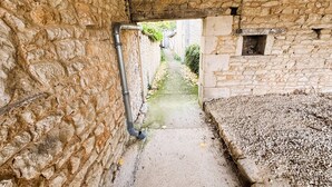 A narrow stone corridor with a concrete path, leading to a doorway. - Gîte des Débats, ideal for families and friends. Pets welcome! (Valence-en-Poitou)
