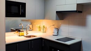 A modern kitchen with a built-in microwave, a sink, a toaster, and a kettle. - Movistar Arena | National Stadium | Caupolicán (Santiago)