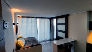 A compact room with a bed, a small desk, and a window with curtains. - Movistar Arena | National Stadium | Caupolicán (Santiago)