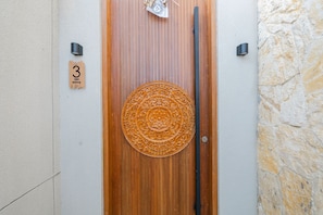 A wooden door with a circular, ornate metal door knocker and a small, decorative item hanging above it. - Villa Bintang Ubud (Ubud)