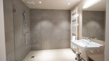 A modern bathroom with a shower, a sink, and a towel rack.