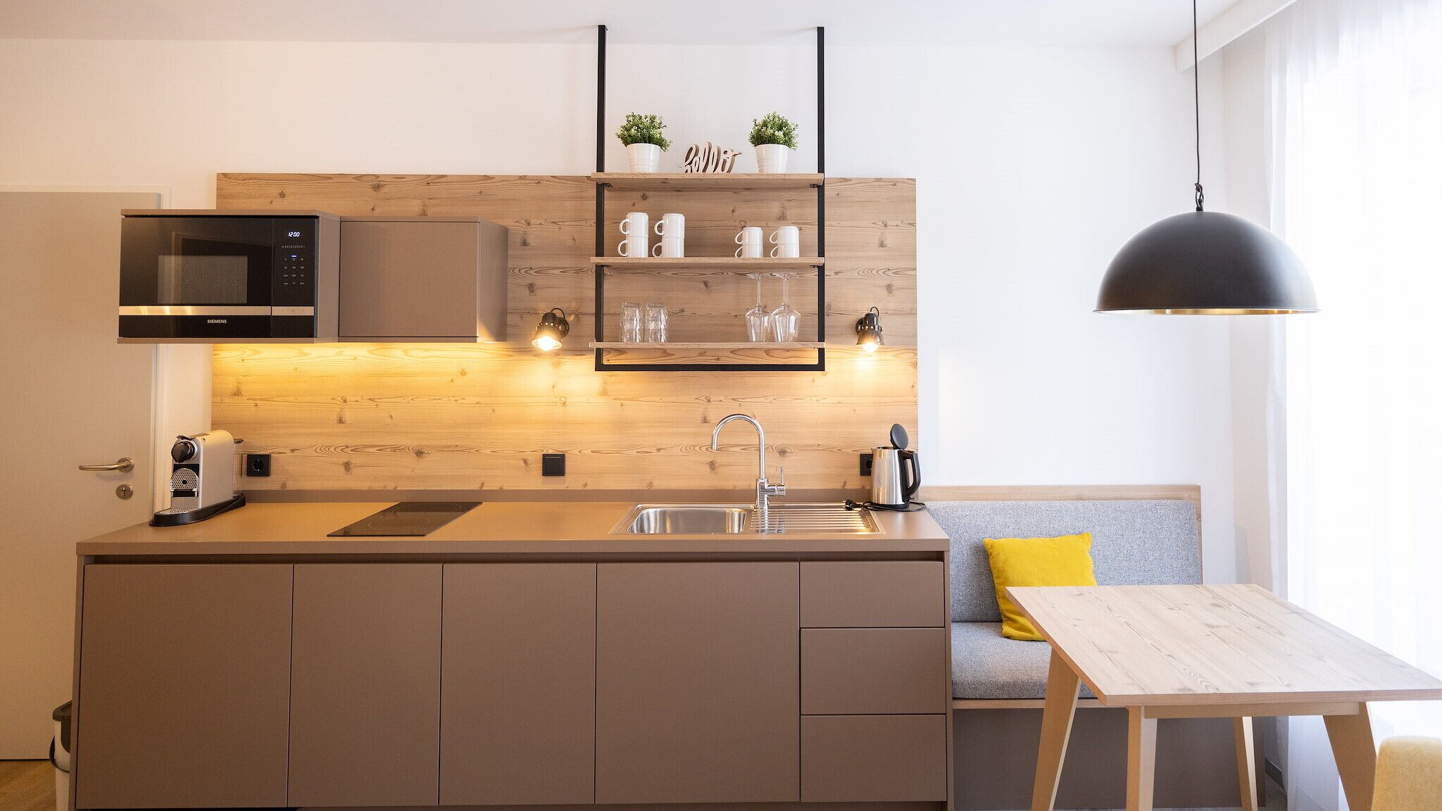 Une cuisine moderne équipée d’un four à micro-ondes encastré, d’un évier et d’un plan de travail en bois.