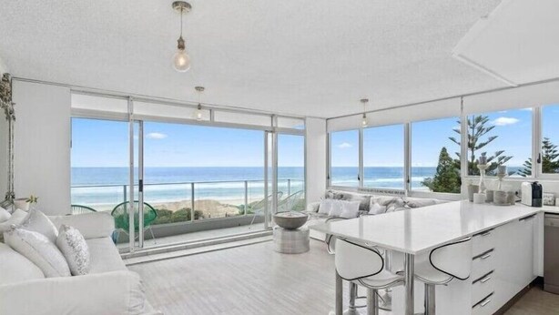 Cozinha moderna com uma ilha grande, banquetas e vista para o oceano.