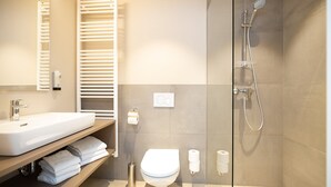 A modern bathroom with a sink, toilet, and shower.