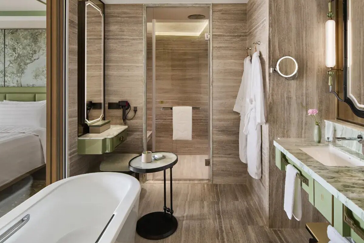 A modern bathroom with a bathtub, a shower, a vanity with a mirror, and a toilet.