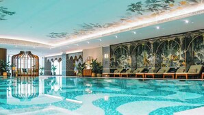 Ein großes Hallenbad mit Liegestühlen und Wandgemälden.