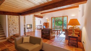 A spacious living area with a wooden ceiling, a sofa, a chair, a table, and a lamp. - La Bergerie – Southern charm all year round (Tourrettes-sur-Loup)