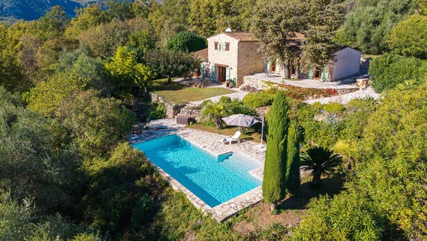 A stone house with a swimming pool surrounded by lush greenery and a mountainous backdrop. - La Bergerie – Southern charm all year round (Tourrettes-sur-Loup)