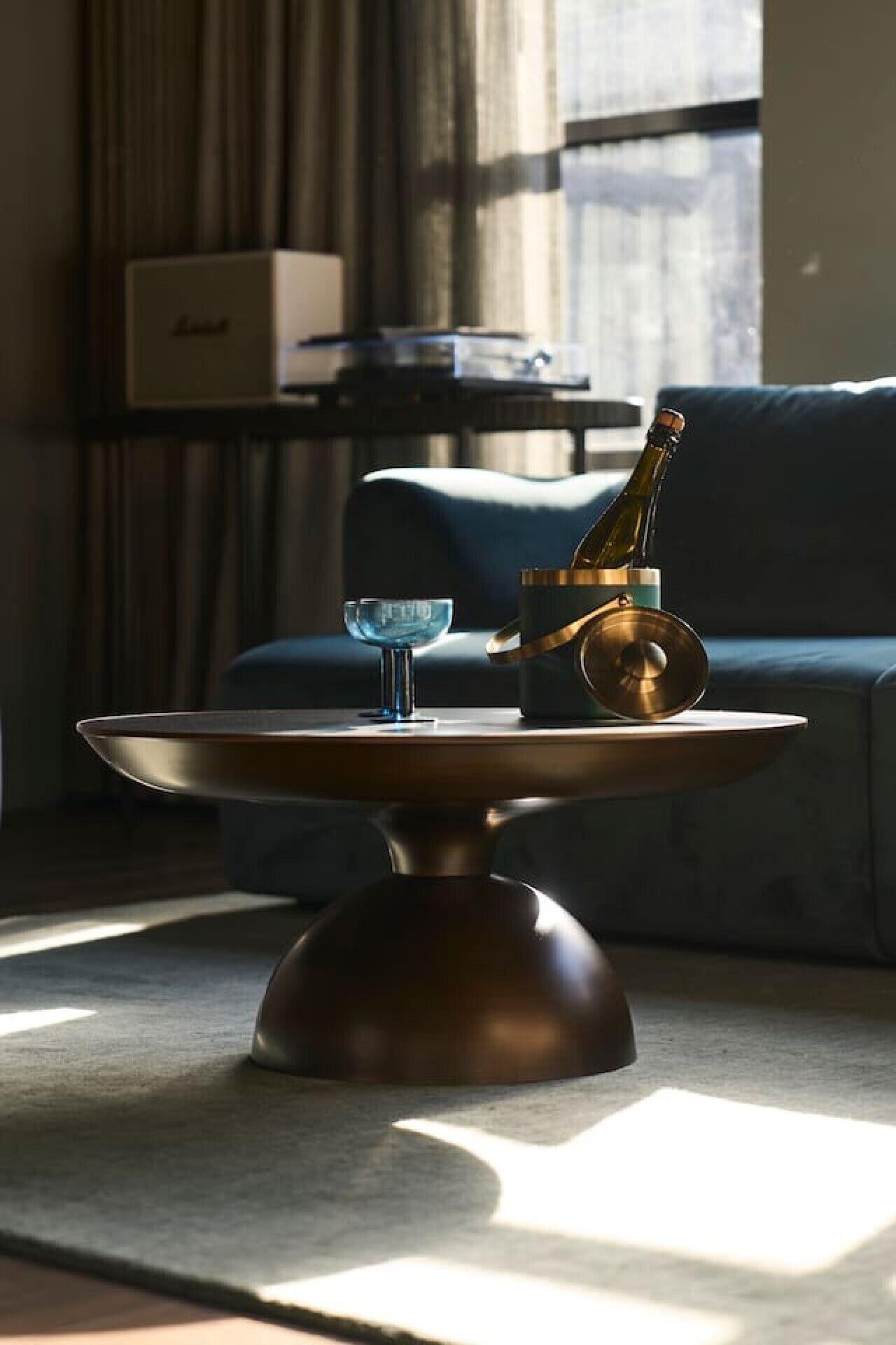 Een moderne woonkamer met een glazen tafel, een fles champagne en een glazen schaal.