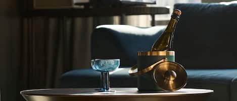 A modern living room with a glass table, a bottle of champagne, and a glass bowl.