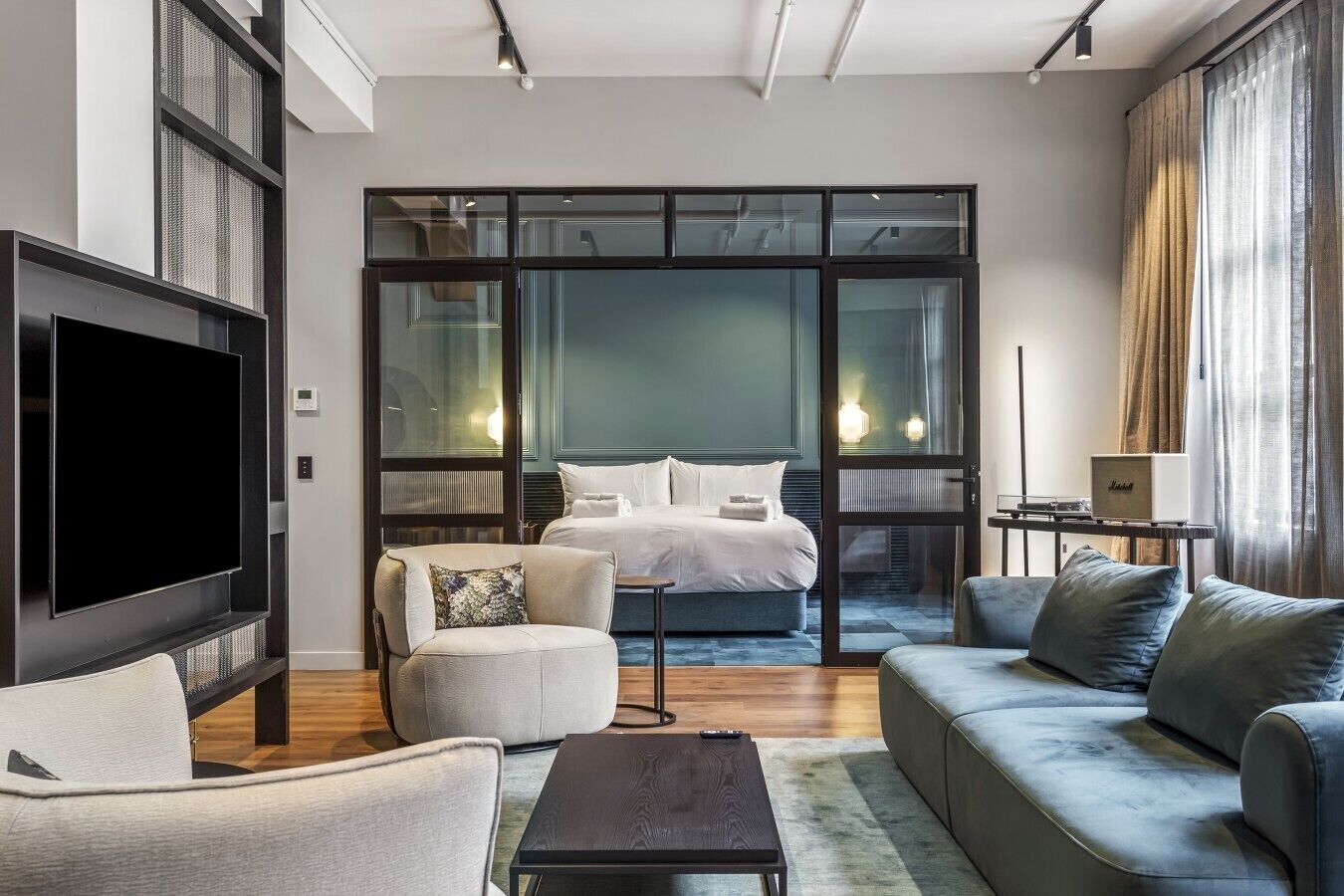 Una habitación de hotel moderna con una cama grande, un televisor de pantalla plana, un sofá y una mesita.
