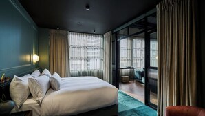 Ett hotellrum med en stor säng, ett skrivbord, en stol och utsikt genom en glasdörr.