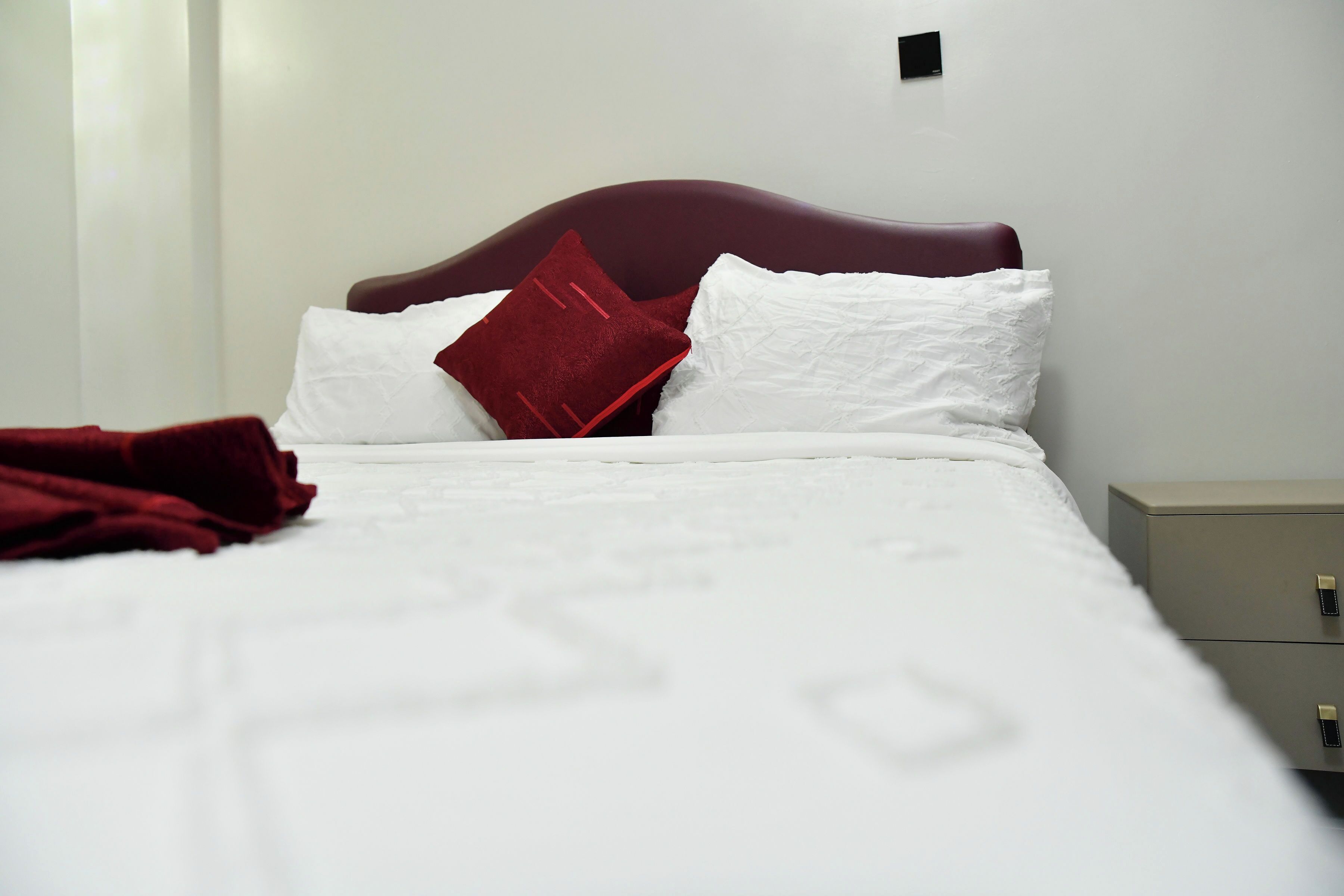 Una cama bien hecha con ropa de cama blanca y una manta roja.