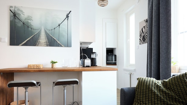 A modern kitchen with a wooden countertop, two bar stools, a coffee machine, and a hanging light fixture. - Beautiful Studio in Heart of Downtown (Turku)