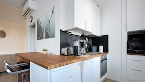 A modern kitchen with white cabinets, a wooden countertop, a Bosch dishwasher, a coffee maker, and a toaster. - Beautiful Studio in Heart of Downtown (Turku)