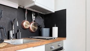 A modern kitchen with white cabinets, stainless steel appliances, a wooden countertop, and copper cookware hanging on the wall. - Beautiful Studio in Heart of Downtown (Turku)