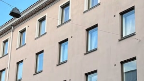 Un immeuble à étages doté d’une façade uniforme, caractérisé par des fenêtres rectangulaires régulièrement espacées et une toiture plate.