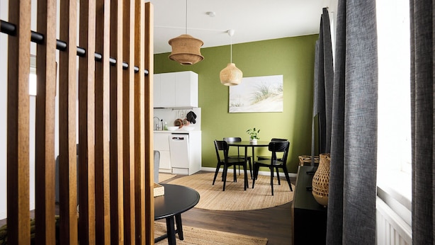 Une cuisine moderne avec des meubles blancs, un coin repas doté d’une table ronde et de chaises, et une grande fenêtre avec des rideaux.