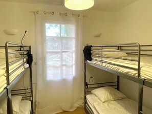 Una habitación con literas, una ventana con cortinas y una lámpara.