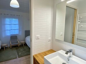 Et moderne badeværelse med en hvid vask, et spejl og et bruseområde.