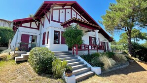 Una casa de dos pisos amb façana vermella i blanca, un porxo d'entrada i una escala cap a l'entrada.