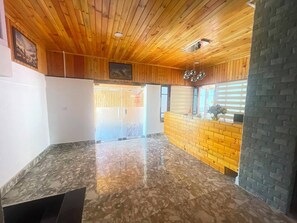 A reception area with a wooden ceiling, a marble floor, and a brick wall. - GaiaYuel (Thimphu)