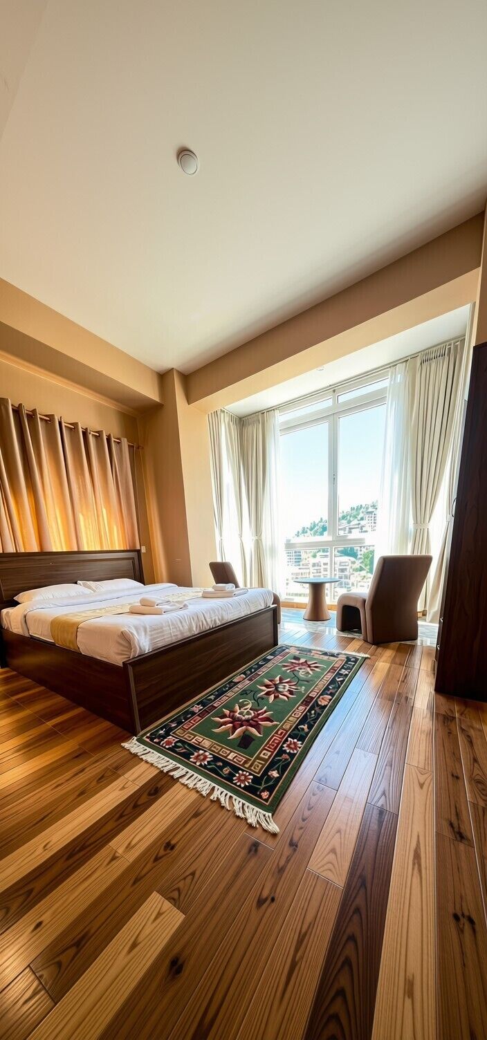 Een hotelkamer met een groot bed, een houten vloer, uitzicht op de stad en een raam met gordijnen.