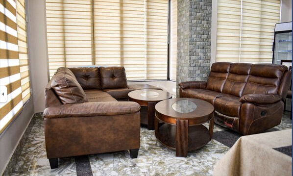 A living room with a sectional sofa, two round coffee tables, and a stone wall. - GaiaYuel (Thimphu)