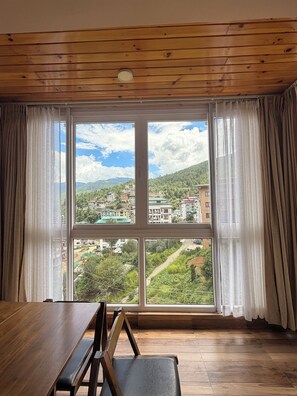 A room with a large window, wooden ceiling, and a dining table with benches. - GaiaYuel (Thimphu)
