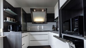 Una cocina moderna con armarios oscuros, encimeras blancas y microondas integrado.