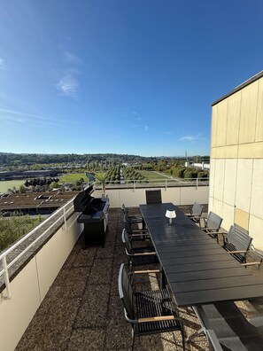 A rooftop terrace with a grill, seating, and a view of the cityscape. - Holiday Apartment 120 m² Penthouse – Europa-Park – Strasbourg – Colmar (Lahr/Schwarzwald)