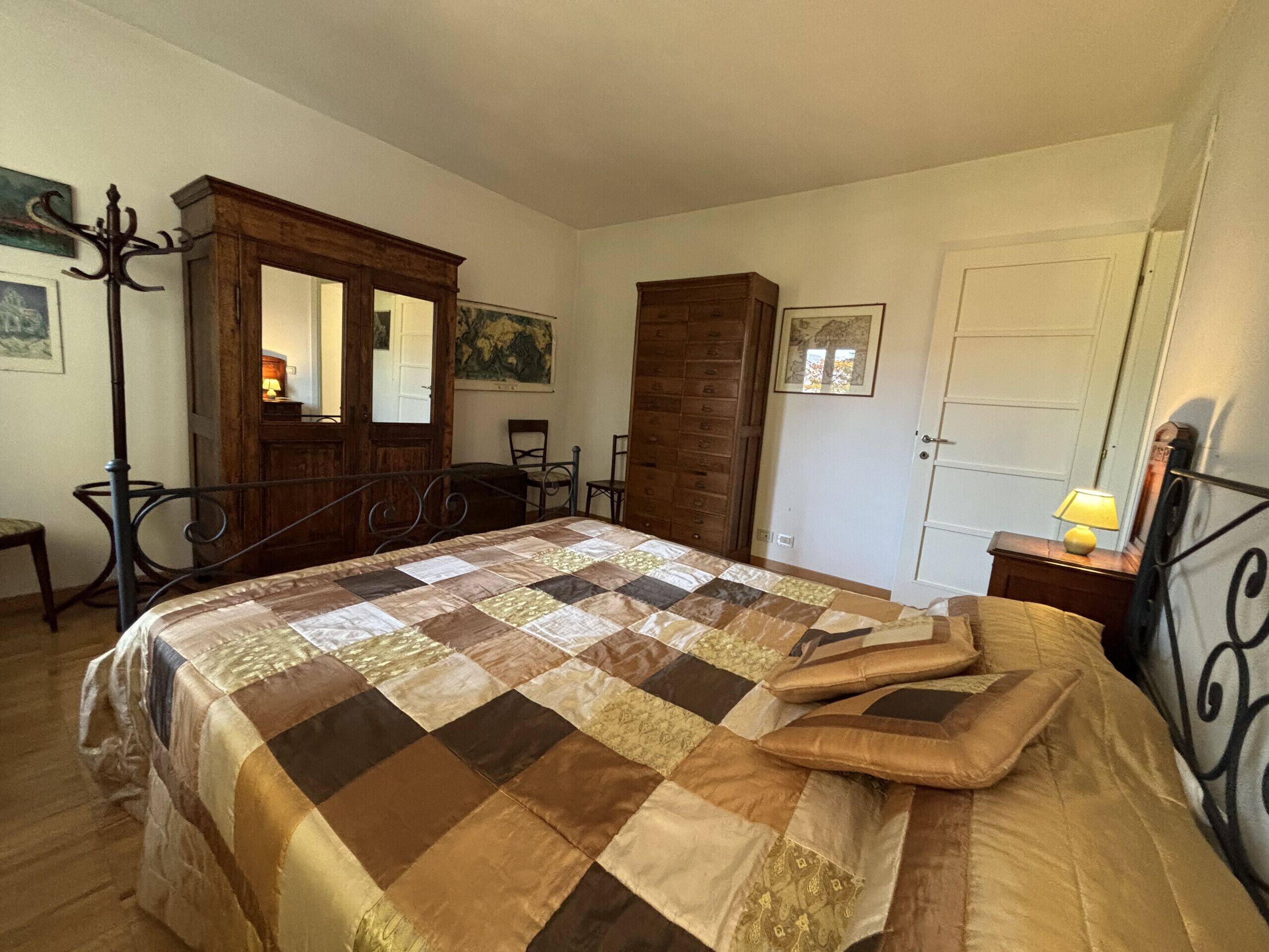 Ein Schlafzimmer mit einem großen Bett, einem Holzschrank, einem Stuhl, einem Schreibtisch und einer Lampe.