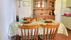 A dining area with a wooden table set for four, surrounded by wooden chairs. A wooden cabinet with glass doors is in the background. - Esther 2 apartment with balcony in Luino (Luino)