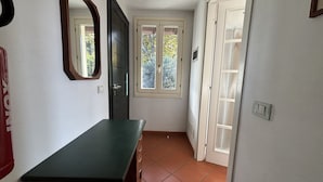 A narrow hallway with a green table, a door, and a window with a view of trees. - Esther 2 apartment with balcony in Luino (Luino)