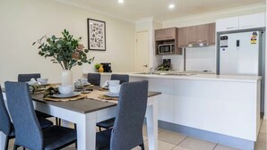 A modern kitchen with white cabinets, a built-in microwave, and a refrigerator.