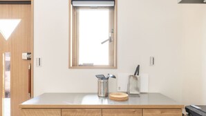 A kitchen with a wooden countertop, a window above the sink, and various kitchen utensils. - The best Nakano house (Nakano City)