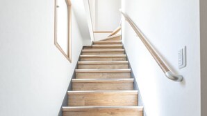 A wooden staircase with a handrail, white walls, and a framed picture on the left. - The best Nakano house (Nakano City)
