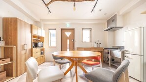 A modern kitchen with a central island, wooden cabinets, and a dining area with a round table and chairs. - The best Nakano house (Nakano City)