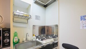 Een kleine keuken met een spoelbak, kookplaat en een spiegel boven het aanrecht.