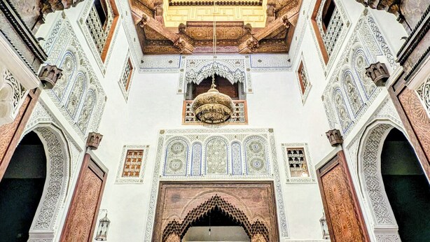 Un intérieur richement décoré, avec des détails architecturaux complexes, notamment des arcades et des motifs élaborés sur les carreaux.