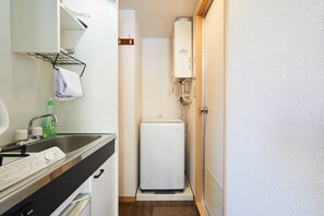 A compact bathroom with a sink, a small mirror, a towel rack, a heater, and a door. - Shinjuku 202 for 2 peoples, private toilet + small kitchen (中野區)